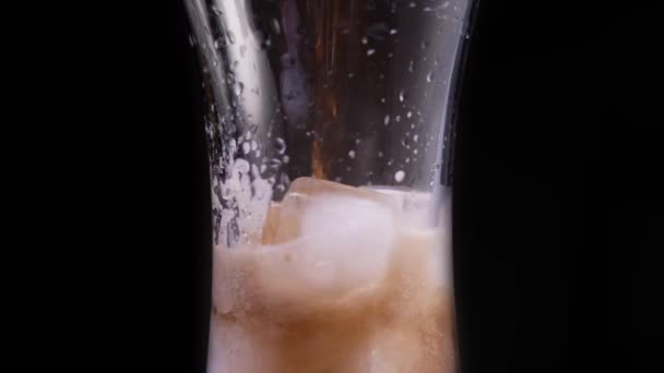 Cola in Großaufnahme mit Eiswürfeln übergießen. Rotierendes Glas mit Cola — Stockvideo