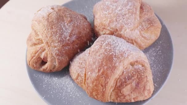 Croissants frescos en un plato. Encima de los croissants con azúcar en polvo — Vídeo de stock