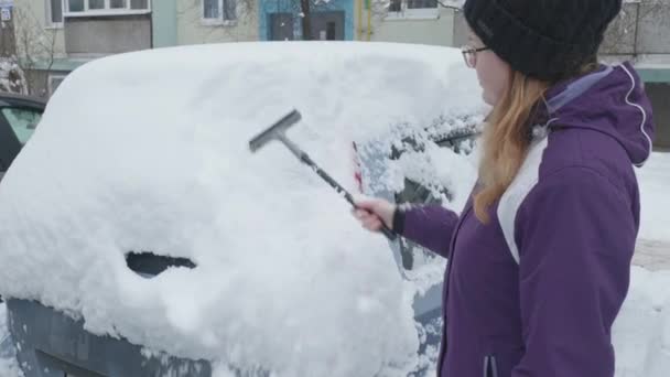Čistí auto od sněhu. Dívka uklízí auto — Stock video