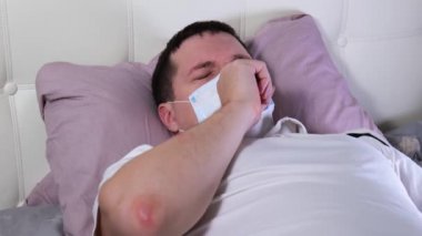 Yatakta yatan beyaz adam sıcaklığı ölçer. covid 19
