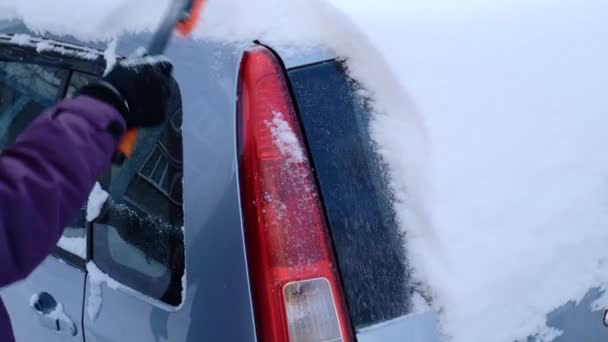 Девушка очищает машину от снега — стоковое видео