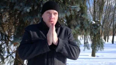 Soğuktaki adam ellerini soğuktan ovar.