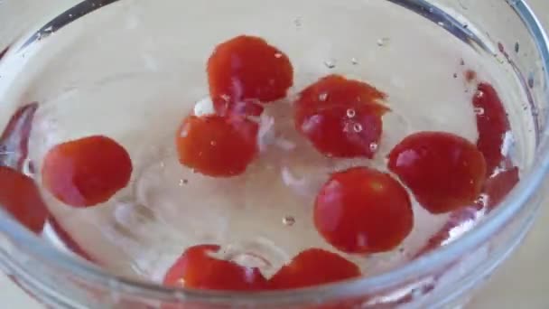 Τα ώριμα ντοματίνια πέφτουν σε ένα μπολ με νερό αργής κίνησης — Αρχείο Βίντεο