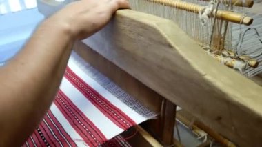 Kumaş tezgahı yakınlaştırıyor. Bir adam satre ahşap dokuma tezgahında kumaş yapıyor.