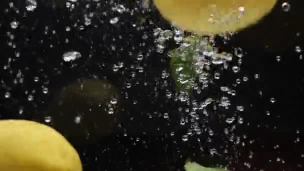 Медленные лимоны падают в воду на черном фоне — стоковое видео