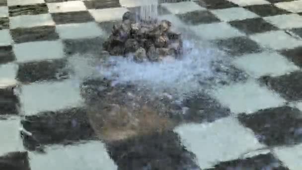 Drops of water falling into the fountain on black and white tiles — Stock Video