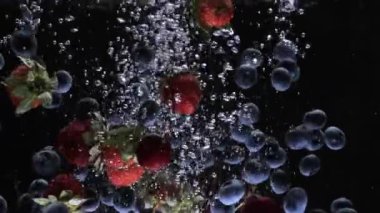 Meyveler yavaş yavaş suya düşer. Çilekli yabanmersinli, süper ağır çekimde.