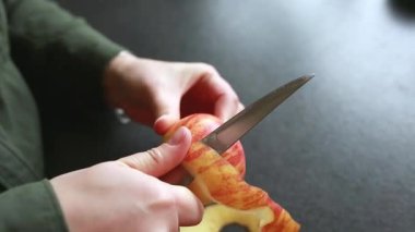 Mutfakta bıçakla taze elma soyan kadın ellerinin yakın çekimi. Yemek hazırlama süreci. Sağlıklı beslenme, ev yemeği, doğal yemek, günlük yaşam tarzı..