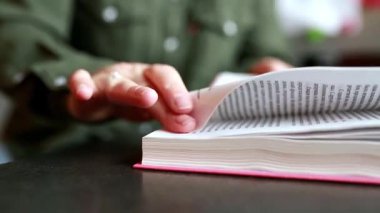 Kitabın sayfalarını çeviren genç bir kadının fotoğrafını çek. Ev içinde sakin okuma süreci, eğitim, öğrenme, odaklanma, boş zaman ve farkındalık kavramı.