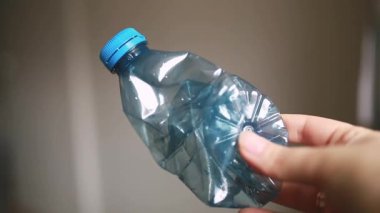 Beyaz mutfak arka planında ezilmiş plastik bir şişeyi kapat. Plastiğin geri dönüşüm, sürdürülebilirlik, çevresel farkındalık ve günlük nesneler gibi temalara uygun dokusu ve şeffaflığını vurgular.