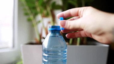 Masadaki plastik şişeyi kapat. Genç bir kadın eli, çevreye duyarlı günlük rutinleri ve geri dönüşümlü nesnelerle etkileşimi vurgulayarak PET kapağını kapatır. Yüksek kaliteli FullHD görüntüler