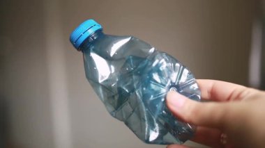 Beyaz mutfak arka planında ezilmiş plastik bir şişeyi kapat. Plastiğin dokusunu ve şeffaflığını vurgular, geri dönüşüm, sürdürülebilirlik, çevre gibi konular için uygundur