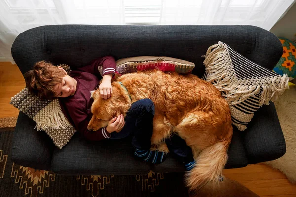 Menino Deitado Sofá Abraçando Cão Golden Retriever — Fotografia de Stock