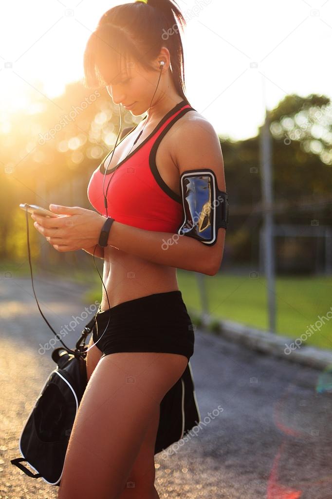 Young fitness woman after train look at her smart phone