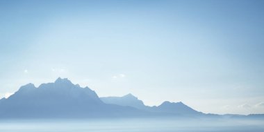 Şafak vakti berrak mavi gökyüzünün altındaki dağ manzarası. Yumuşak güneş ışığı zirveleri.