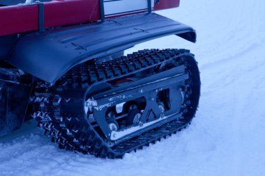 Karlı bir ortamda yer alan dayanıklı materyalleri ve karmaşık mekanikleri vurgulayan kar motosikletli pistin yakın çekimleri, kış sporu ekipmanları ve açık hava keşiflerini gösteriyor