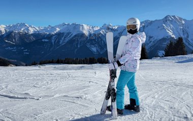 Güneşli bir dağ yamacında kayak yapan bir kayakçının olduğu kış sporları sahnesi dramatik dağ manzarası.