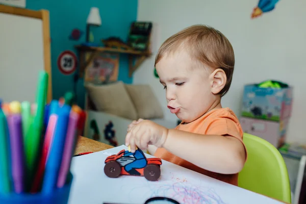 Bambino ragazzo cavalcando la sua moto giocattolo su una strada disegnata su carta . — Foto Stock