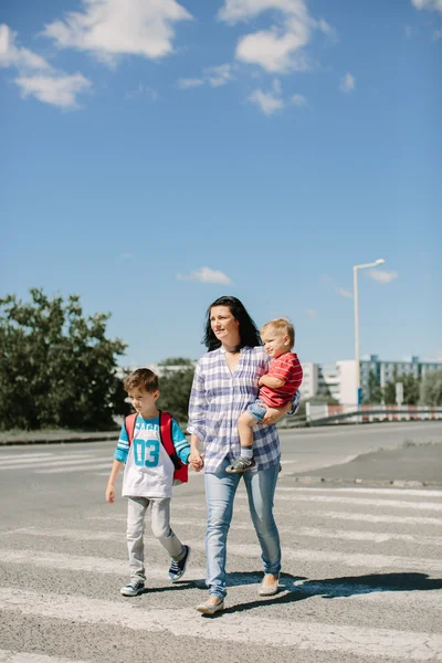 Madre y sus hijos cruzan la calle camino a la escuela . — Foto de Stock