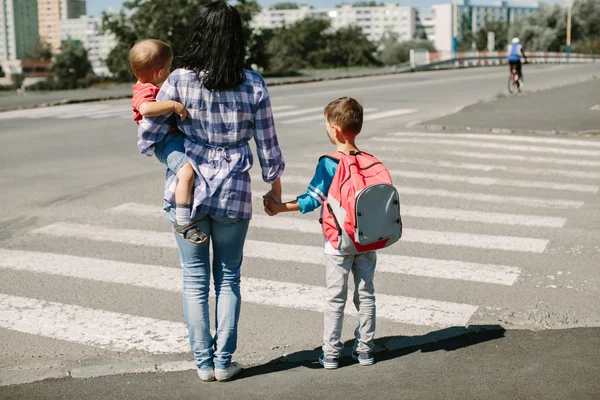 Mãe e seus filhos prestes a atravessar a estrada a caminho da escola . — Fotografia de Stock