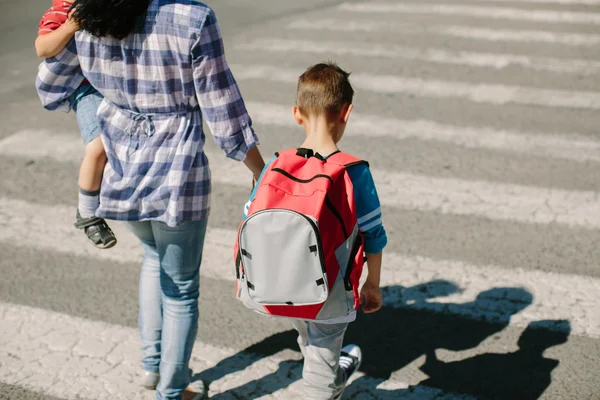 Mor och hennes barn på väg att korsa vägen på väg till skolan. — Stockfoto