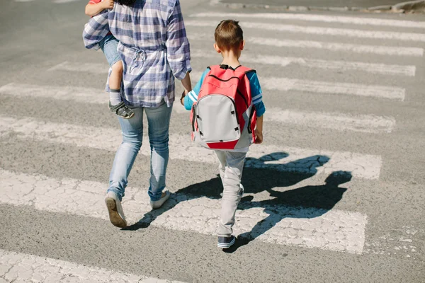 母亲和母亲和她的孩子在上学路上过马路. — 图库照片