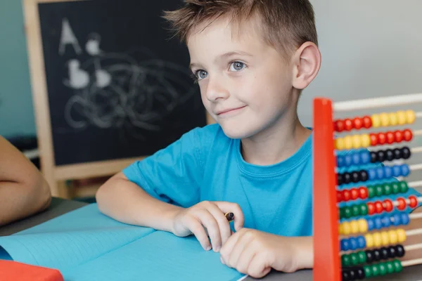 S úsměvem školáka pracuje na úkolem z matematiky — Stock fotografie