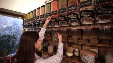 Sıfır Atık Dükkanı 'nda çalışan bir esnaf. Dükkan Asistanı Paketleme Bedava Market 'te Cam Kavanozu Kırmızı Merceklerle Dolduruyor.
