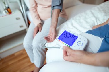 Mavi Ekran 'da İdeal Kan Basıncıyla Otomatik Kollu Kan Basıncı Monitöründen Okumuş. Yaşlı kadın hastanın kan basıncının normal seviyesinde dijital kan basıncı monitörü..