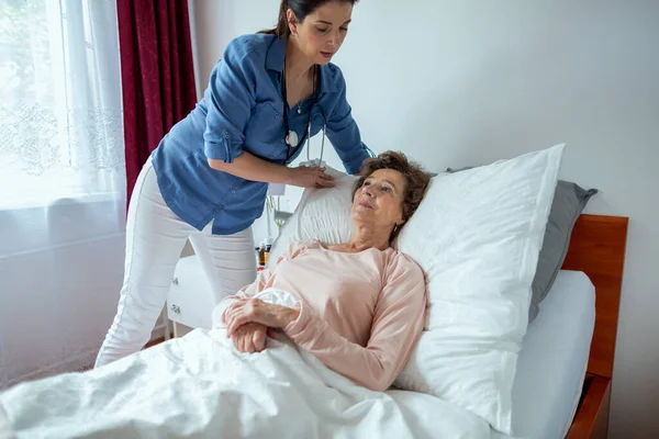 Hauskrankenschwester Macht Älteres Patientenbett Pflegerin Richtet Kissen Für Seniorin Ein Stockbild