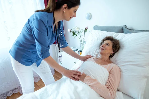 Медсестра Склоняется Над Пожилой Женщиной Лежащей Больничной Койке Старшая Пациентка Стоковая Картинка