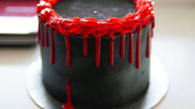 Kırmızı kenarlı, minimalist tasarımı olan siyah tereyağlı pasta.