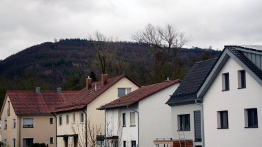 Kırmızı kil kiremitli çatılar ve tuğla duvarlı ön cepheli evler ve görünür bacalar. Avrupa 'da geleneksel konut binaları, mavi gökyüzünün altında fayanslı kiremitli çatılar ve taş duvarlar, samimi şehir manzarası.