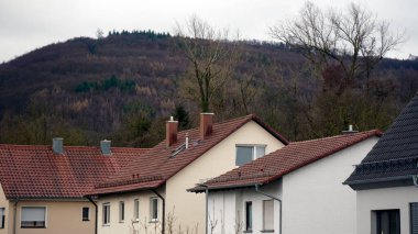 Kırmızı kil kiremitli çatılar ve tuğla duvarlı ön cepheli evler ve görünür bacalar. Avrupa 'da geleneksel konut binaları, mavi gökyüzünün altında fayanslı kiremitli çatılar ve taş duvarlar, samimi şehir manzarası.