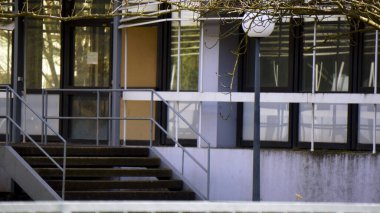 Birkaç mavi çöp torbası dışarıda bir çöp konteynırının yanına konur. Çöp torbaları çöpün yanında duruyor, fazla ev veya park atıkları toplanmayı bekliyor. Olay yeri, kentsel sağlık sorunlarını ve her gün