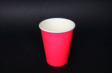 Canlı kırmızı bir kağıt bardak, boş ve dik, koyu siyah bir arka planda keskin bir şekilde göze çarpar. Temiz beyaz iç döşeme ve pürüzsüz dış görünüş onun basit, işlevsel tasarımını vurgular. İçecekler, partiler ve etkinlik içeren kavramlar için mükemmel.