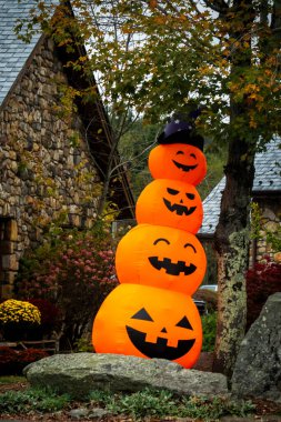 Konforlu bir evin ön bahçesinde, üç büyük balkabağı dikkatle üst üste istiflenerek şenlikli bir gösteri oluşturuldu.