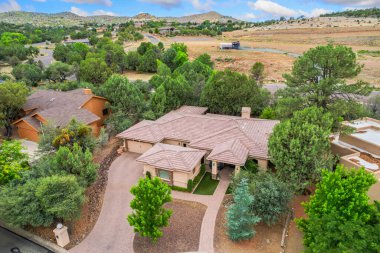 Çok çeşitli uzun ağaçlar ve uzak dağlar arasında yuva yapmış güzel bir evin etkileyici bir hava manzarası.