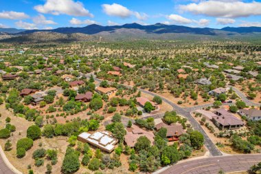 Bu hava manzarası, uzaklardan yükselen görkemli dağların zeminine güzel bir şekilde kurulmuş, pitoresk bir yerleşim alanını gösteriyor.