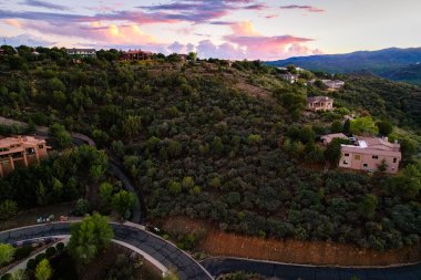 Sagecover arazi üzerinde renkli alacakaranlık, uzak meşe silueti ve yumuşak meşe ile sakin bir akşam sahnesi