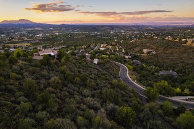 Sagecover arazi üzerinde renkli alacakaranlık, uzak meşe silueti ve yumuşak meşe ile sakin bir akşam sahnesi