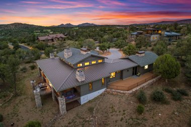 Renkli bir günbatımı sırasında doğa ile çevrili çağdaş bir evin nefes kesici hava görüntüsü mimari ve çevrenin mükemmel bir karışımını sergiliyor..