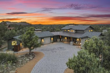 Renkli bir günbatımı sırasında doğa ile çevrili çağdaş bir evin nefes kesici hava görüntüsü mimari ve çevrenin mükemmel bir karışımını sergiliyor..