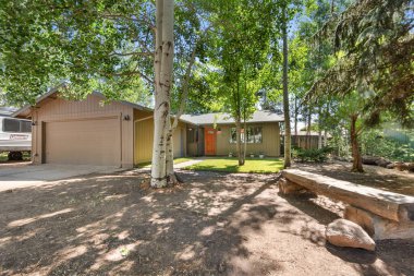 Önünde gururla duran iki büyük ağaçla kocaman bir garajı olan güzel bir ev, bu güzel eve gölge ve güzellik sağlıyor.