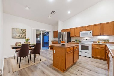 Bu ahşap dolaplar, modern paslanmaz çelik aletler, yemek ve yemek pişirmek için geniş bir ada ve bitişik bir yemek odası olan güzel tasarlanmış bir mutfak.