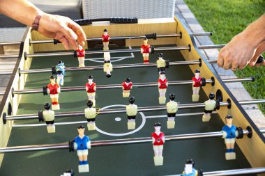 İki birey, eğlence amaçlı aktivitelerine tamamen dalmış, belirlenmiş bir masanın üstünde langırt oynuyorlar.