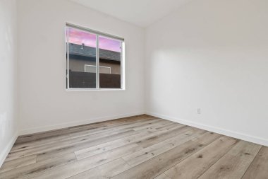 Geniş, boş bir oturma odası. Güzel ahşap döşemeler. Bir tavan vantilatörü tarafından tamamlanmış.