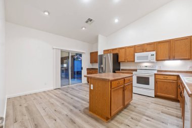 Geniş mutfak tamamen boş. Güzel ahşap dolaplar ve cazibesini arttıran büyük bir merkez ada var.