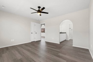 Zarif ahşap döşemeleri ve estetiği geliştirmek için şık bir tavan vantilatörü olan güzel tasarlanmış bir oturma odası.