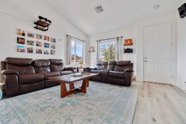 Bu oturma odasında şık bir sehpa ile eşleştirilmiş rahat kahverengi bir kanepe var. Rahatlamak ve toplanmak için davet edici bir alan yaratıyor.